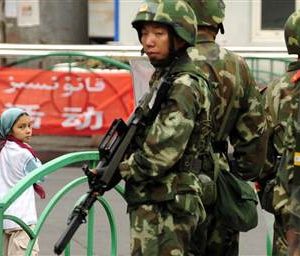 Chinese military personnel stand in front of sign in both Arabic and Chinese. Source: East Turkistan Australian Association 