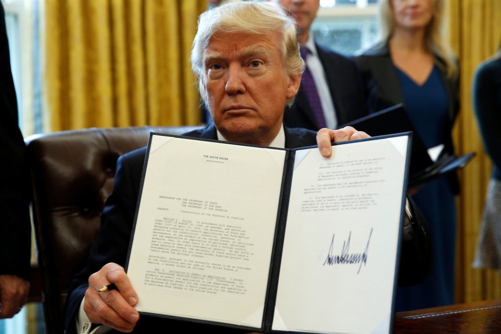 President Donald Trump holding up one of many executive orders signed during his first month in the White House. Source: REUTERS / Kevin Lamarque